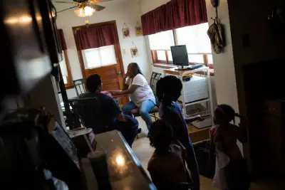 Sylvester and Gladys Clayborn sit in their kitchen as their granddaughters and great niece play nearby. The couple fell into debt when Gladys was permanently disabled after heart surgery. Photo: Edwin Torres/ProPublica