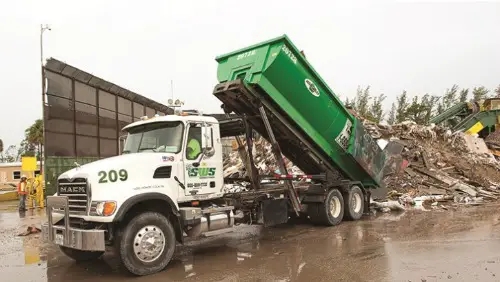 A green and white Southern Waste Systems truck dumping trash